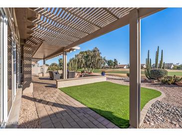 Inviting covered patio overlooking a green lawn and golf course with desert landscaping and comfortable seating at 15701 W Huron Dr, Sun City West, AZ 85375