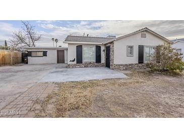 Charming single-story home featuring stucco exterior, black shutters, stone accents, and a spacious concrete driveway at 625 W Central Ave, Coolidge, AZ 85128