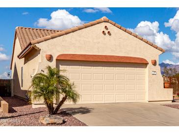 Beige stucco home featuring a wide garage, red clay roof tiles and a well kept yard at 8142 S Open Trail Ln, Gold Canyon, AZ 85118