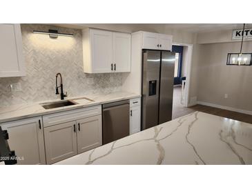 Bright kitchen featuring white cabinets, stainless steel appliances, quartz countertops, and modern backsplash at 13406 N 100Th Ave, Sun City, AZ 85351