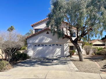 Charming two-story home with white stucco, tile roof and a large shade tree in the front yard at 13517 N 102Nd Pl, Scottsdale, AZ 85260