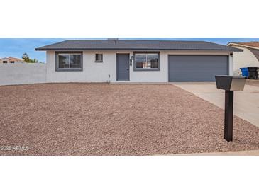 Charming single-story home with desert landscaping and a gray two-car garage door at 702 N Evergreen St, Gilbert, AZ 85233