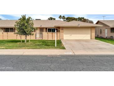 Charming single-story brick home with well-manicured lawn and attached two-car garage at 10646 W Tropicana Cir, Sun City, AZ 85351