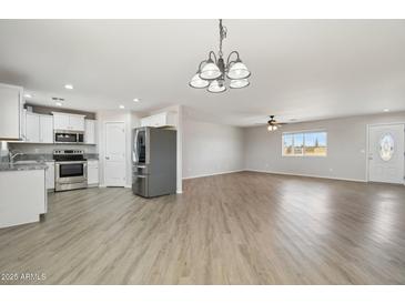 Open-concept living space featuring wood-look floors, modern lighting fixtures, and stainless steel appliances at 21189 E Blue Jay Ln, Florence, AZ 85132