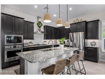 Modern kitchen featuring dark cabinets, a granite countertop island with seating, and stainless steel appliances at 21413 N 59Th St, Phoenix, AZ 85054