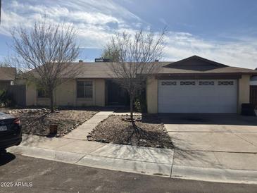 Charming single-story home with a two-car garage, gravel landscaping, and mature trees at 5323 W Seldon Ln, Glendale, AZ 85302