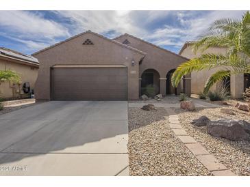 Inviting single-story home with a two-car garage, desert landscaping, and a charming walkway at 7525 W Springfield Way, Florence, AZ 85132