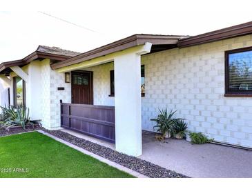 Charming single-story home with textured white brick, a gated porch, and manicured landscaping at 8335 E Montecito Ave, Scottsdale, AZ 85251