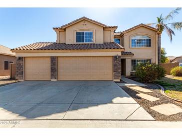 Two story home featuring a tile roof, three car garage, and neutral desert landscaping at 835 E Stirrup Ln, San Tan Valley, AZ 85143