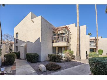 Stylish stucco two-story condo with a private balcony, lush landscaping, and mature palm trees at 9275 E Mission Ln # 206, Scottsdale, AZ 85258