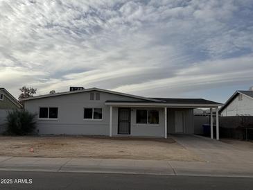 Charming single-story home with a covered parking and a well-maintained front yard at 1853 W Burgess Ln, Phoenix, AZ 85041