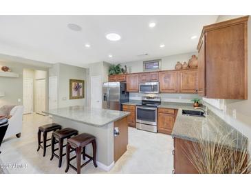 Bright kitchen features granite counters, center island with seating, and stainless appliances at 20462 N Ridgewood Ln, Surprise, AZ 85374