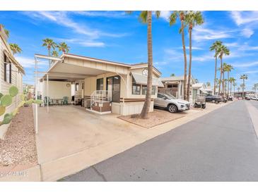 Inviting mobile home featuring a carport, front porch, and well-maintained landscaping with palm trees at 1152 S Sioux Dr, Apache Junction, AZ 85119