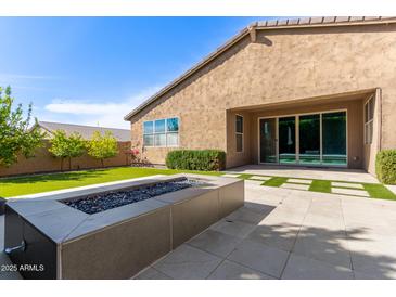 Backyard featuring green grass, a modern fire pit, and a covered patio at 3025 W Night Owl Ln, Phoenix, AZ 85085