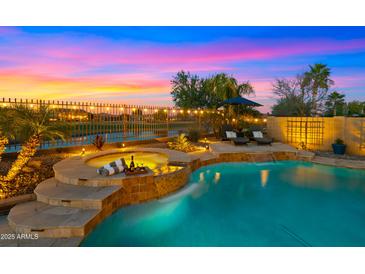 Inviting pool and spa featuring a waterfall, lounge chairs, lush landscaping, and beautiful sunset views at 3400 E Isaiah Ave, Gilbert, AZ 85298