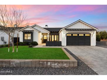 Charming two-story home with white siding, black accents, a manicured lawn, and a paved driveway at 3538 E Glenrosa Ave, Phoenix, AZ 85018