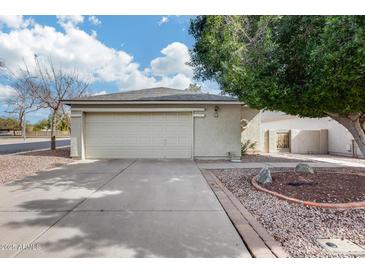 Charming home featuring a two-car garage with a concrete driveway, complemented by desert landscaping and mature trees at 4725 E Brown Rd # 59, Mesa, AZ 85205