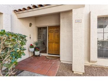 Inviting front entrance features a warm, wood door, terracotta tile, and decorative plants at 7800 E Lincoln Dr # 1007, Scottsdale, AZ 85250