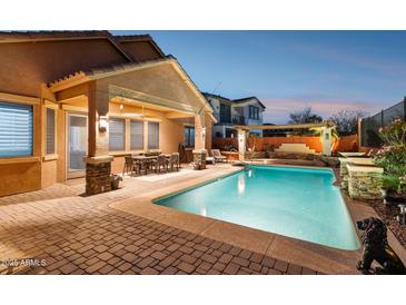 Backyard pool with brick pavers, a covered patio with an outdoor dining set, and lounge chairs at 13849 S 179Th Ave, Goodyear, AZ 85338