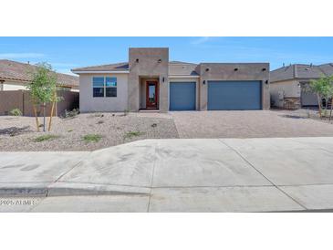 Stunning single-story home featuring a paver driveway, blue garage doors, and minimalist desert landscaping at 18444 W Mohave St, Goodyear, AZ 85338