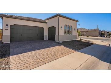 Exterior angle of a home showing a three car garage and a brick driveway at 551 E Citrus Hollow Way, Queen Creek, AZ 85140