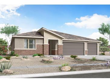 Charming single-story home showcasing desert landscaping, a brick facade, and an attached three-car garage at 18441 W Mohave St, Goodyear, AZ 85338
