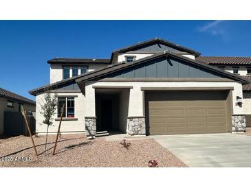 Two-story home featuring a two-car garage, stone accents, and a well-manicured yard under a clear blue sky at 25330 W Bowker St, Buckeye, AZ 85326