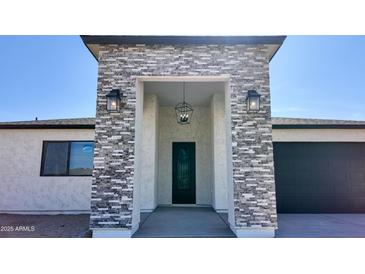Inviting front entrance with stone accents, modern lighting, and a stylish black door at 11612 S 211Th Ln, Buckeye, AZ 85326