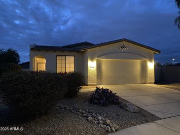 Charming single-Gathering home with a two-car garage, desert landscaping, and warm exterior lighting at dusk at 15222 N 138Th Dr, Surprise, AZ 85379