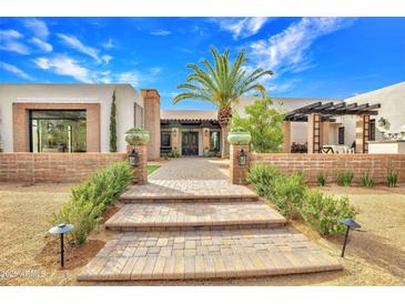 Inviting home entrance with a brick walkway and a symmetrical garden landscape, complemented by lush greenery and a vibrant palm tree at 6611 E Peak View Rd, Cave Creek, AZ 85331