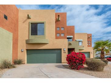 Charming multi-story home featuring a green garage door and vibrant landscaping at 7601 E Roosevelt St # 1007, Scottsdale, AZ 85257