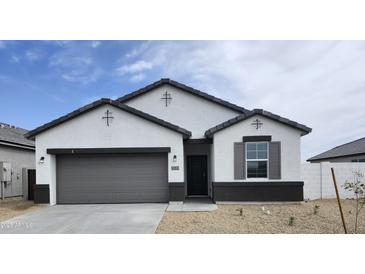 Charming single-story home featuring a gray garage door, dark accents, and a well-maintained, low maintenance front yard at 1531 S 239Th Dr, Buckeye, AZ 85326