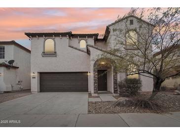 Charming stucco two-story home boasts a two-car garage and arched entry with stone accents at 2502 S 90Th Gln, Tolleson, AZ 85353