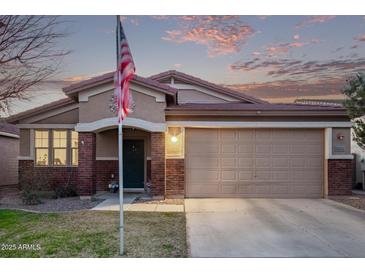 Charming single-story home featuring a two-car garage and welcoming front porch, complete with American flag at 38208 N La Grange Ln, San Tan Valley, AZ 85140