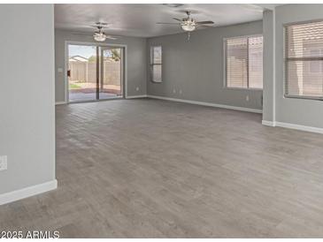 Spacious living room features wood-look floors, neutral paint, sliding glass doors, and ample natural light at 9734 W Carol Ave, Peoria, AZ 85345