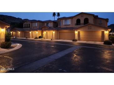 A street view of townhomes with attached garages and desert landscaping at nighttime at 10655 N 9Th St # 204, Phoenix, AZ 85020