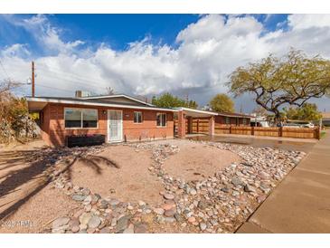 Charming single-story brick home featuring a covered carport and unique rock landscaping in the front yard at 1512 W Fairmont Dr, Tempe, AZ 85282