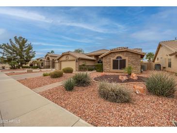 Charming single-story home with desert landscaping, a paved driveway, and a stone accent wall at 18730 N 89Th Ave, Peoria, AZ 85382