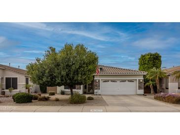 Cozy home featuring manicured landscaping, mature trees, and a classic two-car garage at 9213 W Clara Ln, Peoria, AZ 85382