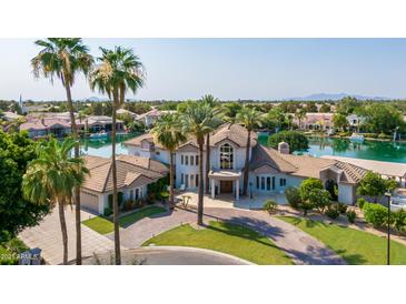 Stunning aerial view of a luxurious waterfront estate with mature palm trees and lush landscaping at 1502 E Treasure Cove Dr, Gilbert, AZ 85234