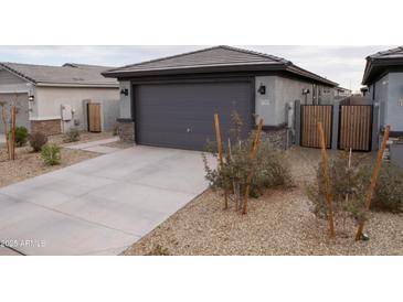 Contemporary home featuring a gray garage door, desert landscaping, and modern exterior lighting at 17353 W Via De Luna Dr, Surprise, AZ 85387