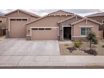 Charming single-story home showcasing a three-car garage, stone accents, and desert landscaping at 24757 N 175 Dr, Surprise, AZ 85387