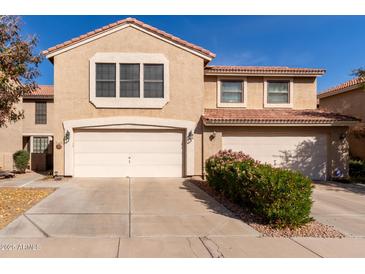Two-story home featuring a three-car garage, tile roof, and a tidy yard with mature landscaping at 4122 E Jojoba Rd, Phoenix, AZ 85044