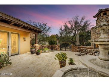 Outdoor patio featuring a stone fountain, desert landscaping and colorful sunset at 10798 E Hedgehog Pl, Scottsdale, AZ 85262