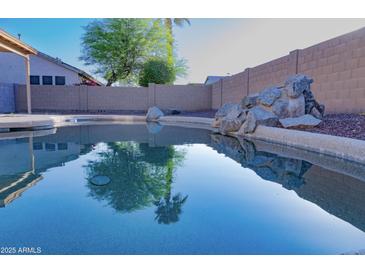 Backyard pool area featuring desert landscaping, a rock feature with palm tree reflections at 16132 W Ironwood St, Surprise, AZ 85374