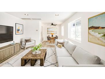 Bright living room with a large sofa, modern decor, and an adjacent dining area bathed in natural light at 3322 E Willetta St, Phoenix, AZ 85008