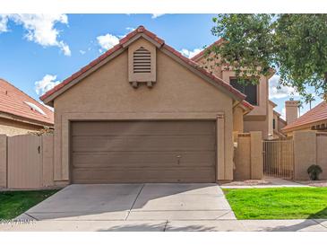 Attached garage with brown door and driveway of a tan stucco home under a partly cloudy sky at 4683 W Dublin St, Chandler, AZ 85226