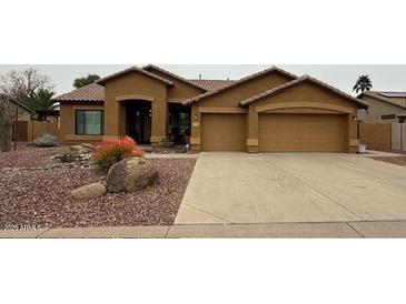 Charming home featuring a tile roof, desert landscaping, and a spacious three-car garage at 6881 W Greenbriar Dr, Glendale, AZ 85308