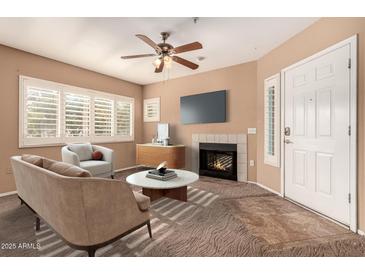 Inviting living room with a fireplace, ceiling fan, and bright windows with plantation shutters at 1295 N Ash St # 125, Gilbert, AZ 85233