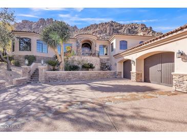 Elegant stucco home with three-car garage, stone accents, desert landscaping, and majestic mountain backdrop at 25572 N 113Th Way, Scottsdale, AZ 85255